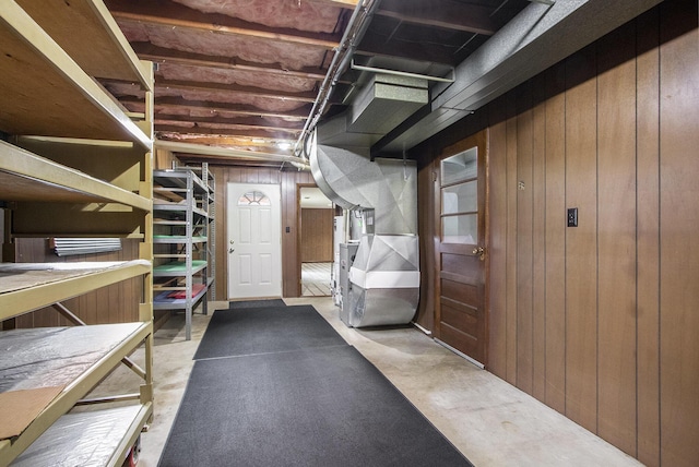 basement featuring heating unit and wood walls