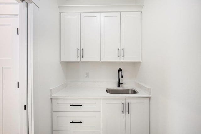 bar with white cabinetry and sink