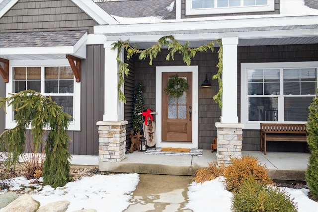 snow covered property entrance with covered porch