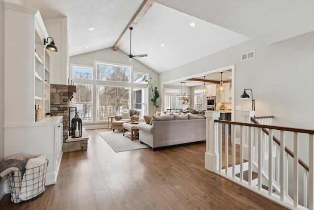 living room with a stone fireplace, high vaulted ceiling, beam ceiling, dark hardwood / wood-style flooring, and ceiling fan with notable chandelier