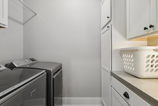 clothes washing area with cabinets and washer and dryer