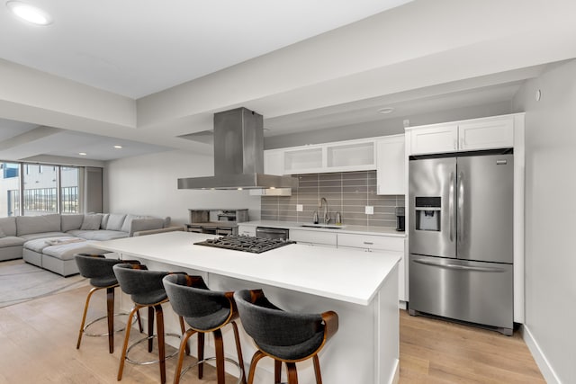 kitchen with tasteful backsplash, stainless steel fridge with ice dispenser, white cabinetry, island range hood, and sink