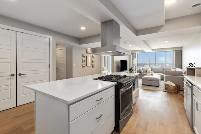 kitchen with a kitchen island, island exhaust hood, light hardwood / wood-style flooring, and appliances with stainless steel finishes