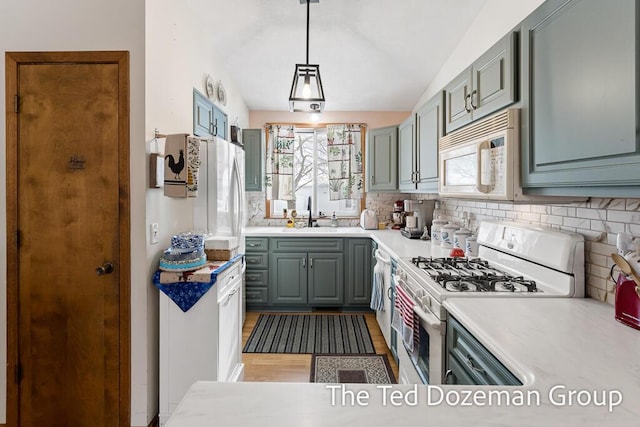 kitchen with lofted ceiling, sink, white appliances, tasteful backsplash, and decorative light fixtures