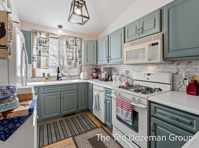 kitchen with lofted ceiling, sink, white appliances, light hardwood / wood-style floors, and decorative backsplash