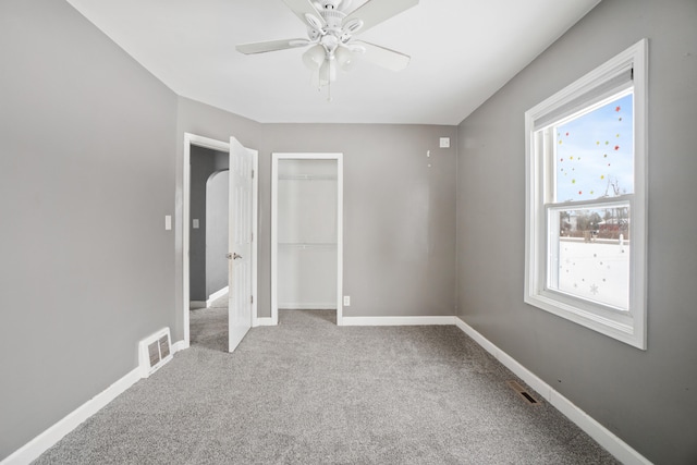 unfurnished bedroom featuring multiple windows, light colored carpet, a closet, and ceiling fan