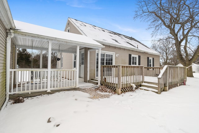 snow covered back of property with a wooden deck