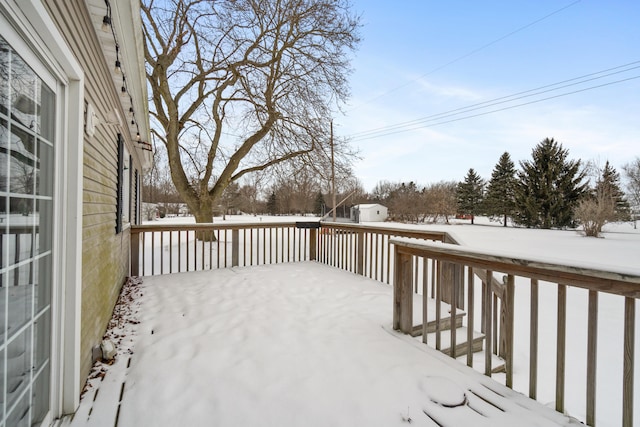 snow covered deck featuring a shed