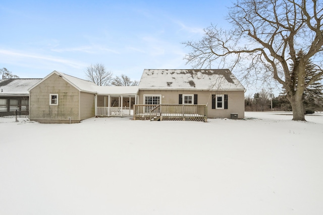 snow covered rear of property with a wooden deck and central AC unit