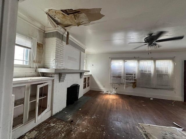 unfurnished living room featuring a brick fireplace, dark hardwood / wood-style flooring, crown molding, and ceiling fan