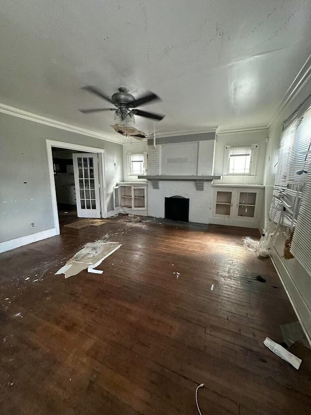 unfurnished living room featuring crown molding, a brick fireplace, dark hardwood / wood-style floors, and ceiling fan