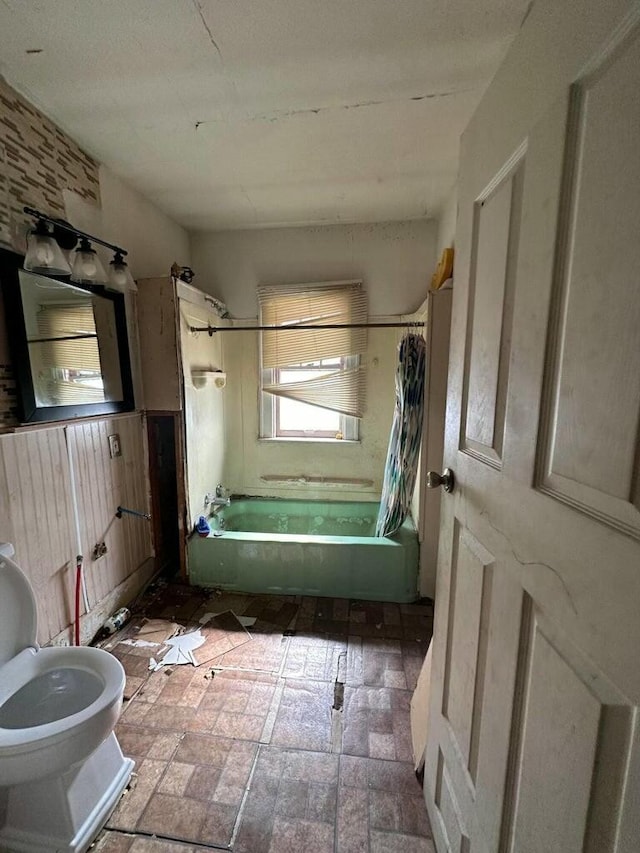 bathroom featuring shower / bath combo, wood walls, and toilet