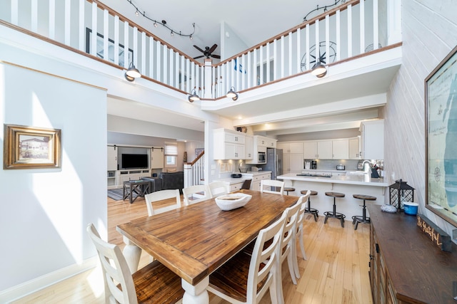 dining space with a towering ceiling and light hardwood / wood-style floors