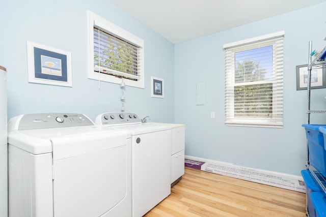 clothes washing area with washing machine and dryer and light wood-type flooring