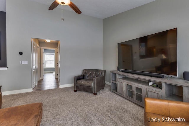 carpeted living room featuring ceiling fan and a towering ceiling