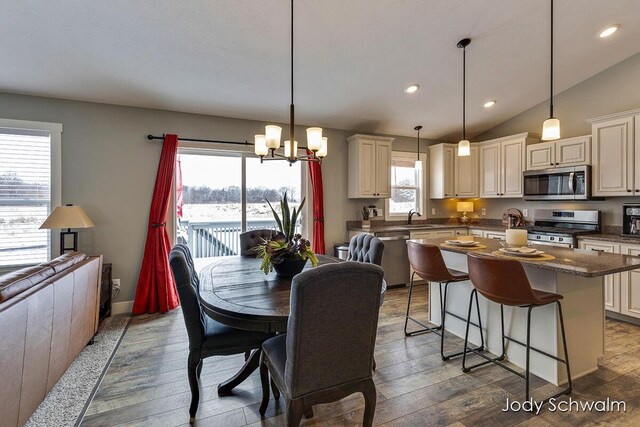 dining room featuring lofted ceiling, sink, an inviting chandelier, and dark hardwood / wood-style floors