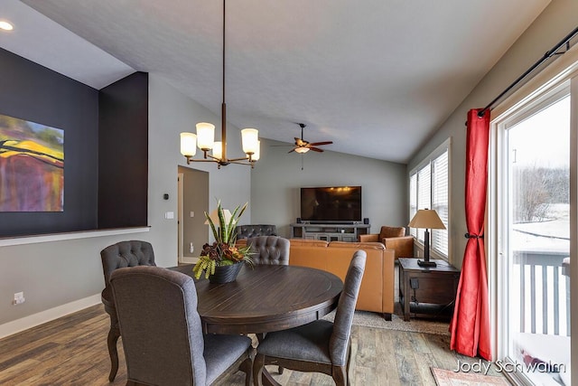 dining space with lofted ceiling, hardwood / wood-style floors, and a notable chandelier