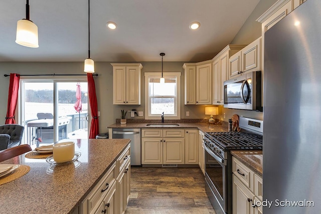 kitchen featuring stainless steel appliances, sink, cream cabinetry, and decorative light fixtures