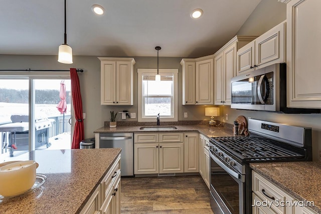 kitchen with appliances with stainless steel finishes, sink, cream cabinetry, and decorative light fixtures