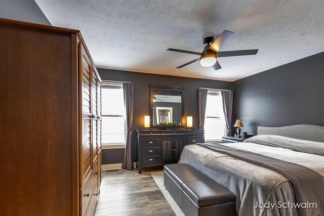 bedroom with dark hardwood / wood-style flooring, a textured ceiling, and ceiling fan