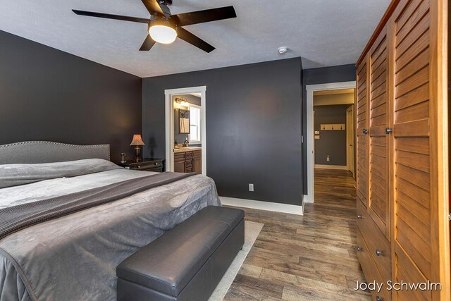 bedroom with ceiling fan, ensuite bath, dark wood-type flooring, and a textured ceiling