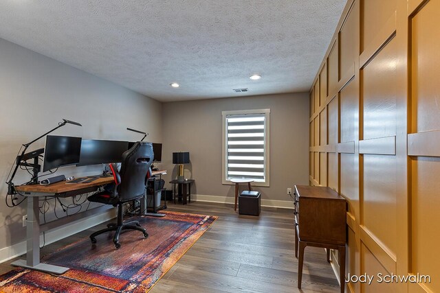 home office with dark wood-type flooring and a textured ceiling