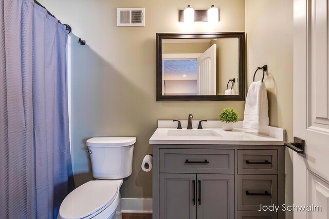 bathroom featuring walk in shower, vanity, and toilet