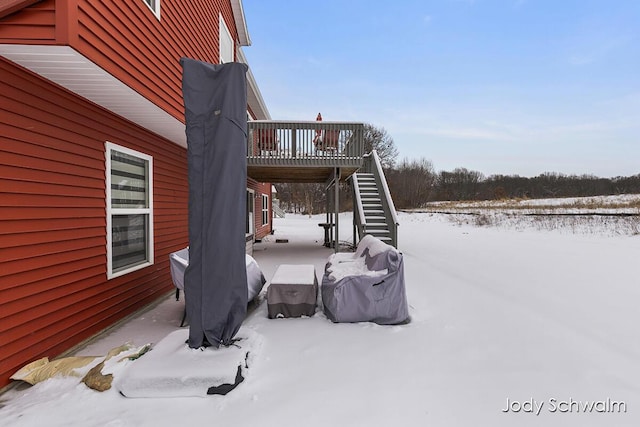 snow covered patio with a wooden deck