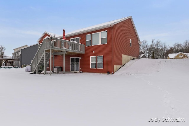 snow covered back of property featuring a wooden deck