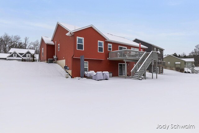 snow covered rear of property with a deck