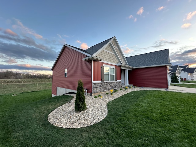 view of side of home with a garage, a lawn, stone siding, and roof with shingles