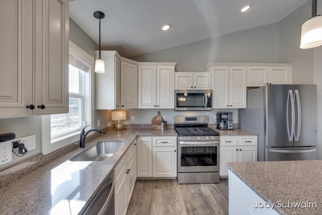 kitchen featuring lofted ceiling, white cabinets, appliances with stainless steel finishes, and a sink