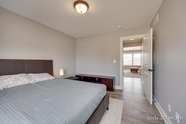 bedroom featuring visible vents, baseboards, and wood finished floors