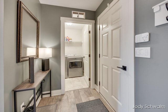 hallway with baseboards, light wood-type flooring, washer / clothes dryer, and visible vents