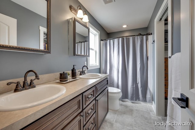 bathroom with a sink, toilet, double vanity, and tile patterned floors