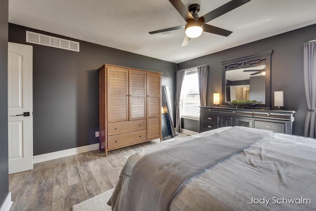 bedroom featuring ceiling fan, wood finished floors, visible vents, and baseboards