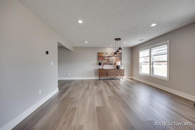 unfurnished living room with visible vents, recessed lighting, wood finished floors, and baseboards