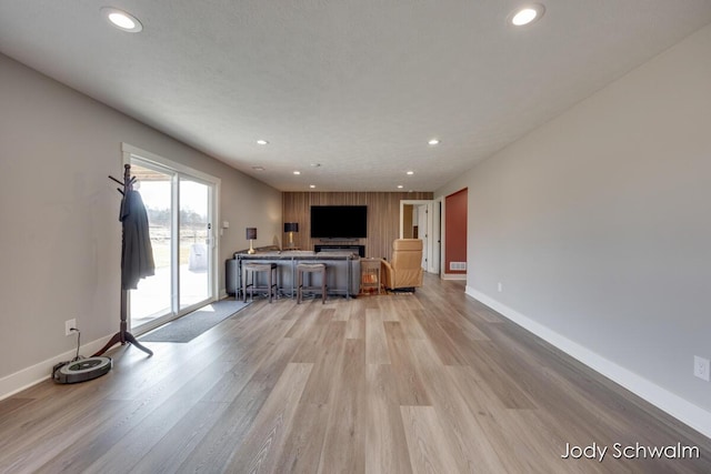 unfurnished living room with light wood finished floors, recessed lighting, and baseboards