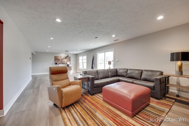 living area with recessed lighting, wood finished floors, baseboards, and a textured ceiling