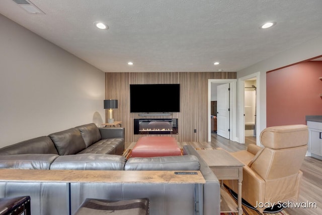 living room featuring recessed lighting, light wood-type flooring, a textured ceiling, and visible vents