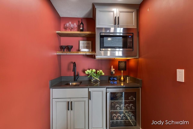 bar featuring a sink, stainless steel microwave, wine cooler, and wet bar