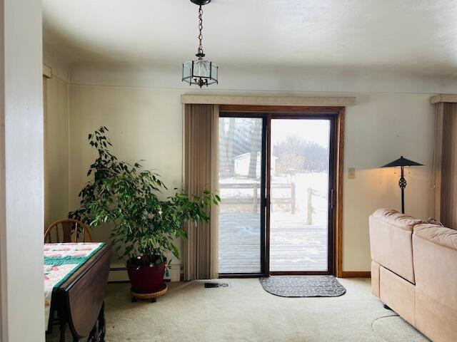 doorway to outside featuring a baseboard heating unit and light colored carpet