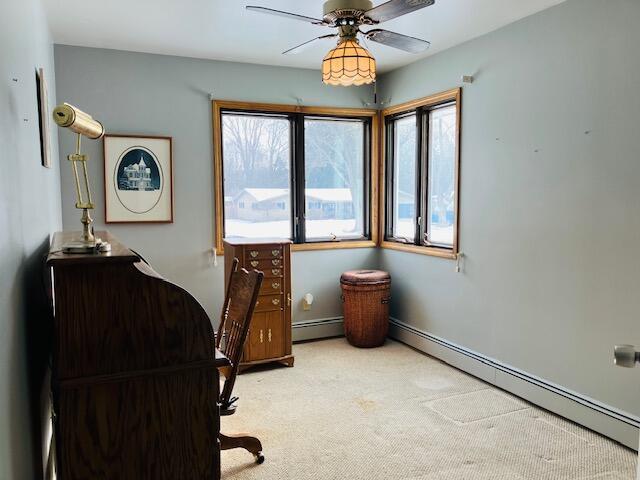 carpeted office featuring a baseboard heating unit, a wealth of natural light, and ceiling fan