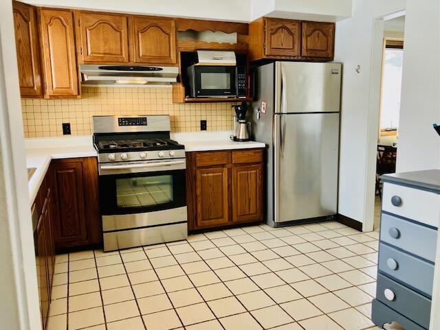 kitchen with tasteful backsplash, light tile patterned floors, and appliances with stainless steel finishes