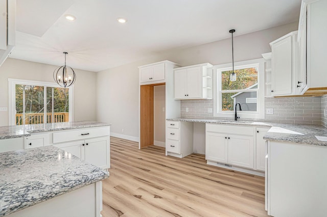 kitchen with pendant lighting, sink, light hardwood / wood-style flooring, and white cabinets