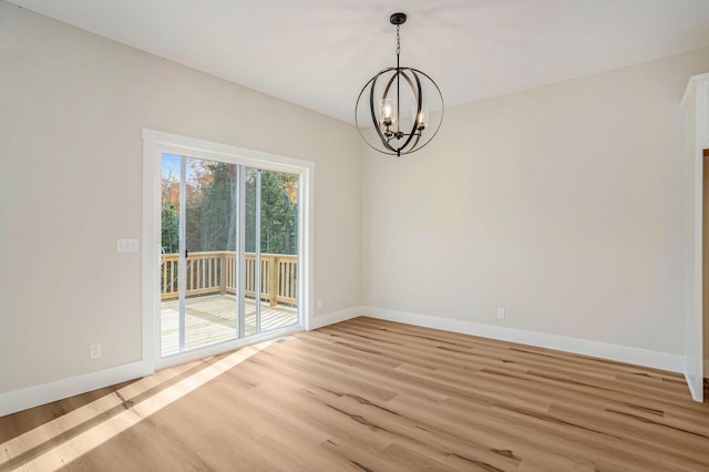 spare room with a chandelier and light hardwood / wood-style floors