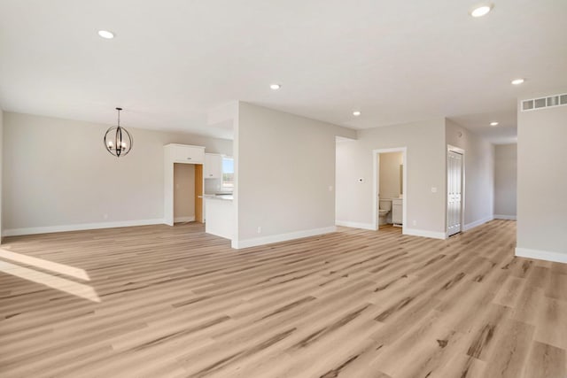 unfurnished living room with a notable chandelier and light wood-type flooring