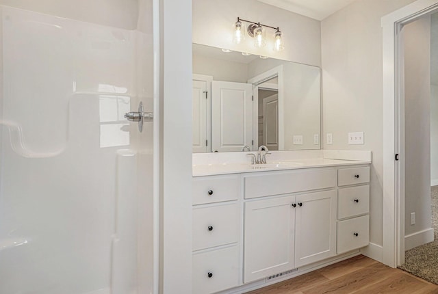 bathroom with wood-type flooring, vanity, and walk in shower