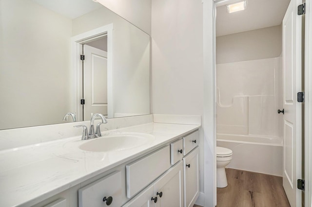 full bathroom with hardwood / wood-style flooring, vanity, shower / tub combination, and toilet