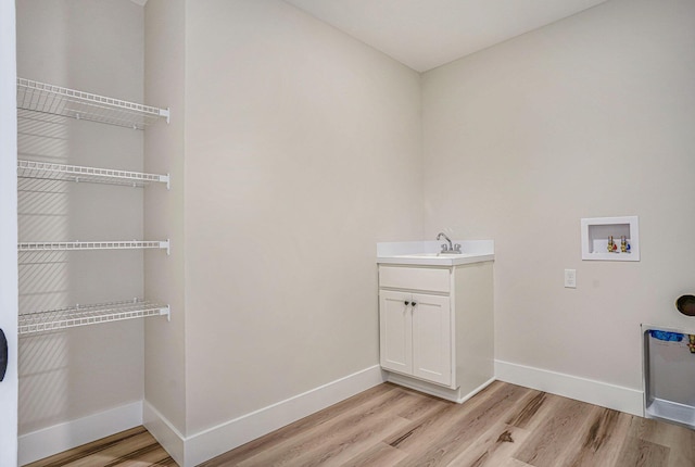 laundry area with cabinets, sink, light hardwood / wood-style floors, and hookup for a washing machine